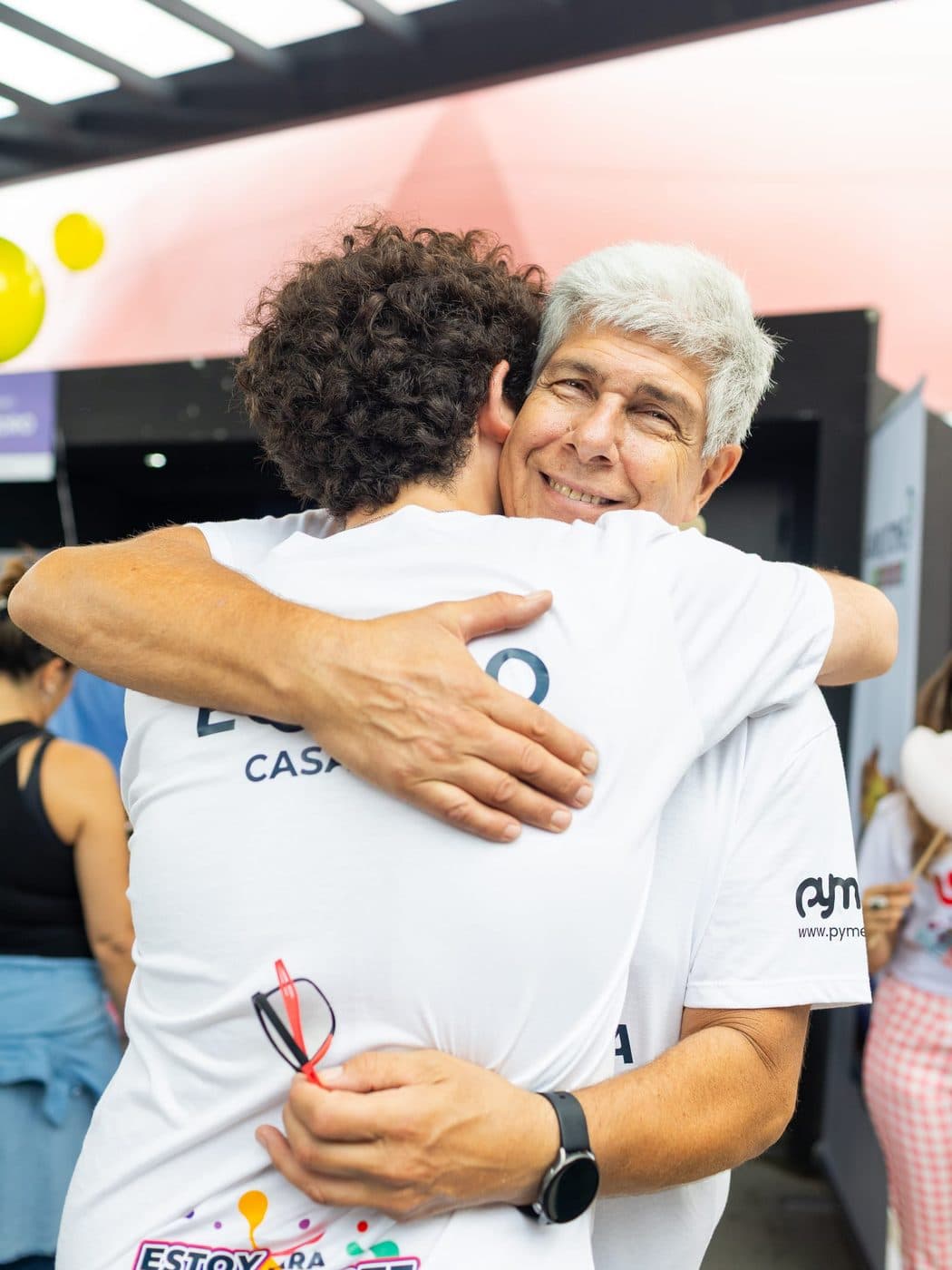 Dos personas de Casacusia se abrazan en un encuentro; una lleva una remera que dice "Estoy para escucharte"